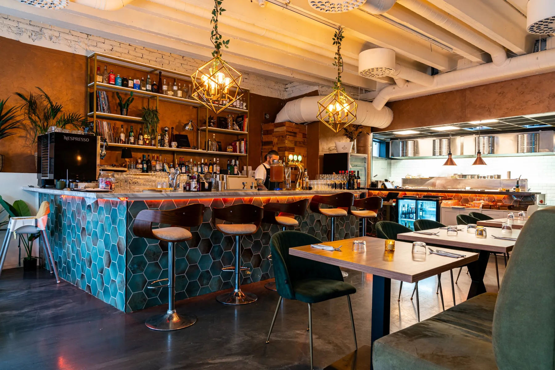 The hexagon-tiled bar at Nabo with gold pendant lamps and bar stools