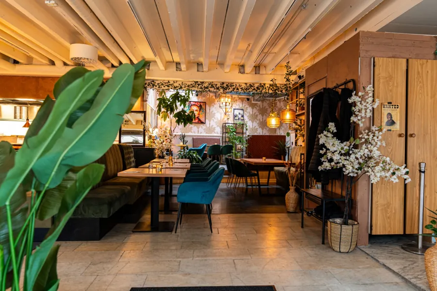 Entrance with plants, velvet seating and the dining room beyond